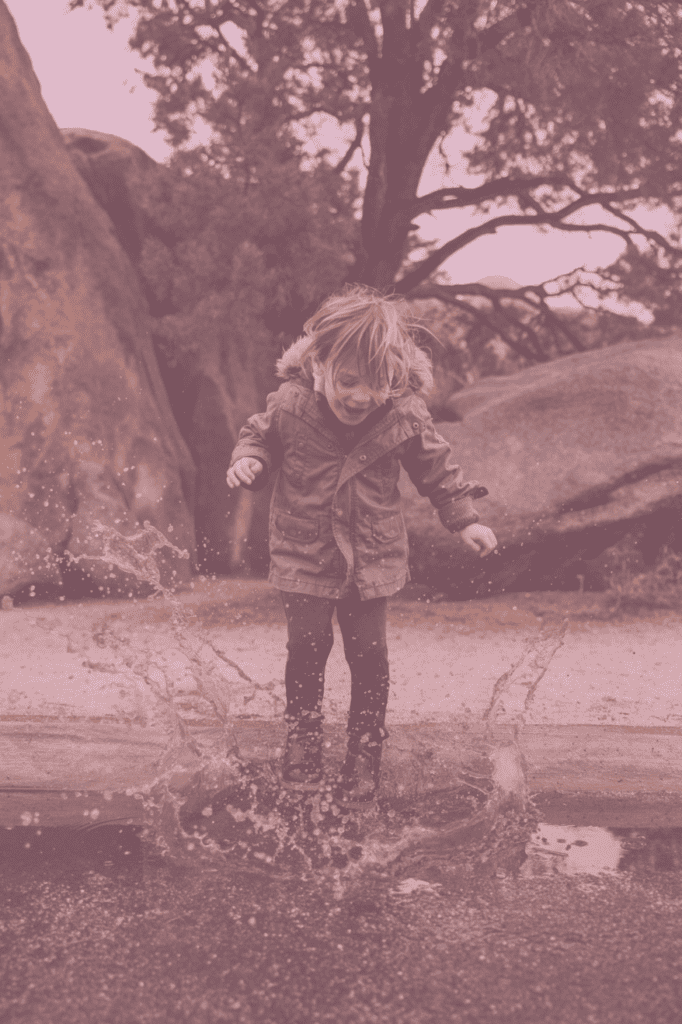 Kind springt in eine Wasserlache und lacht