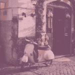 Vespa, parkiert in einer Gasse auf Pflastersteinen vor einer alt aussehenden Tür.