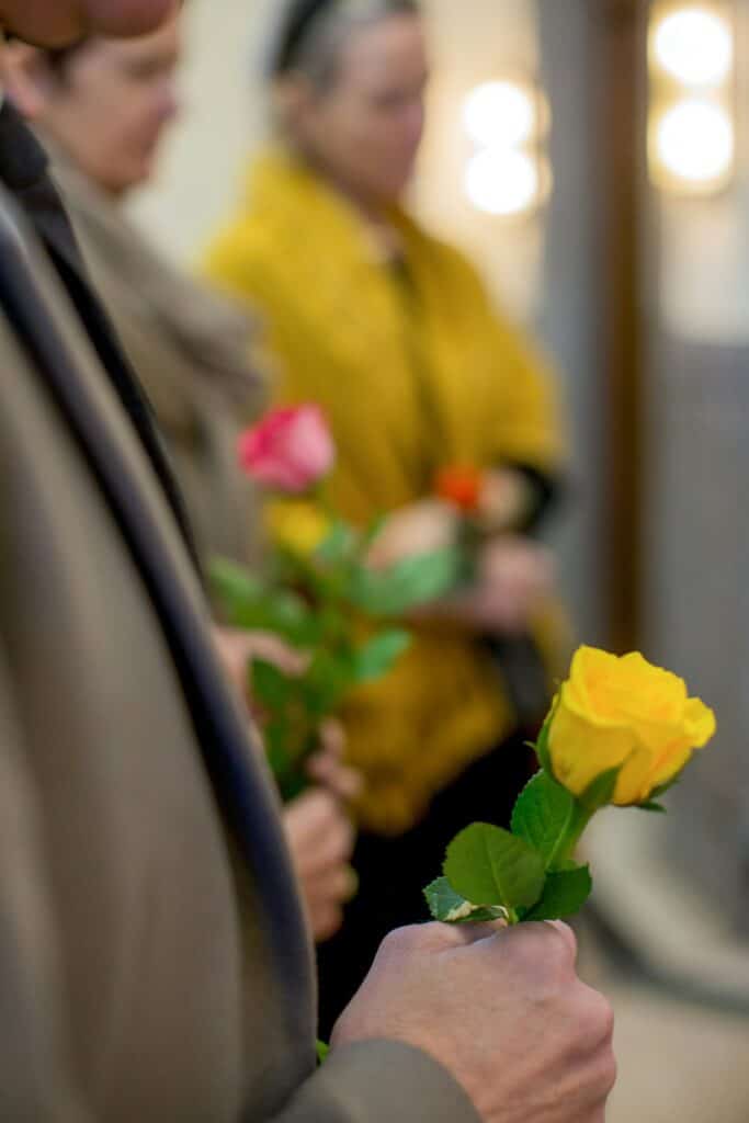 Nahaufnahme von Menschen, unscharf, mit je einer farbigen Rose in der Hand