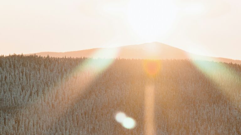 Sonnenstrahlen scheint über verschneiten Hügel und Wald